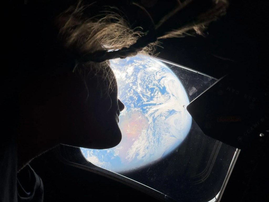 Christina Koch on board of the Artemis II looks out a window at the Earth
